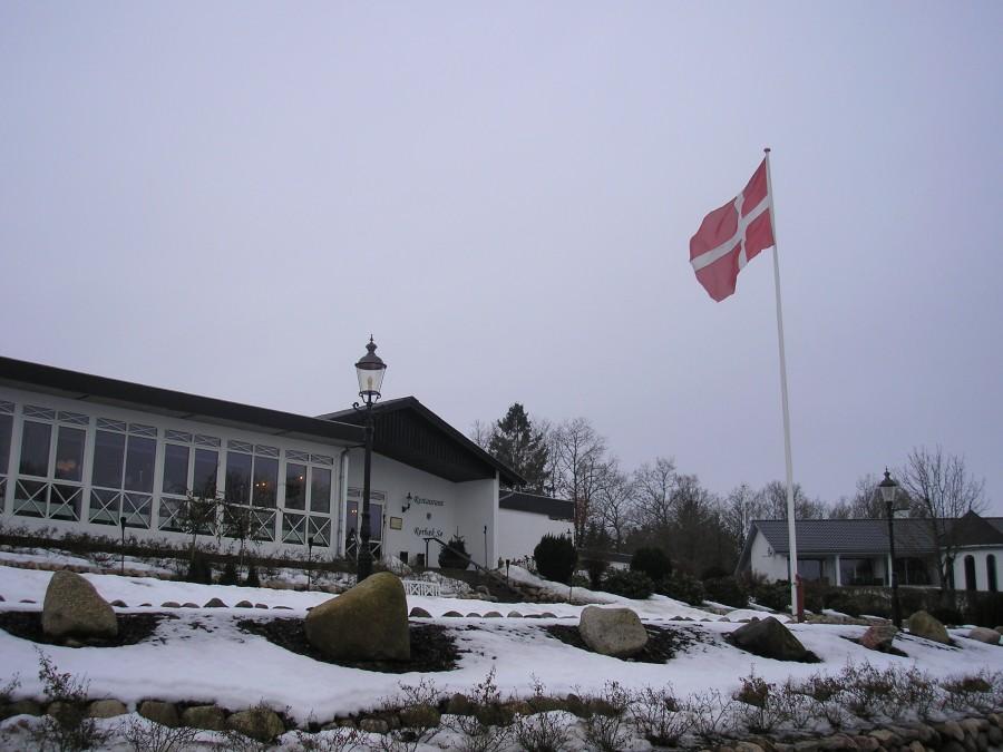 Restaurant Rørbæk Sø z powiewającą duńską flagą. Dannebrog to nieodłączny element tożsamości narodowej Duńczyków. Flaga na maszcie to częsty element w krajobrazie Danii