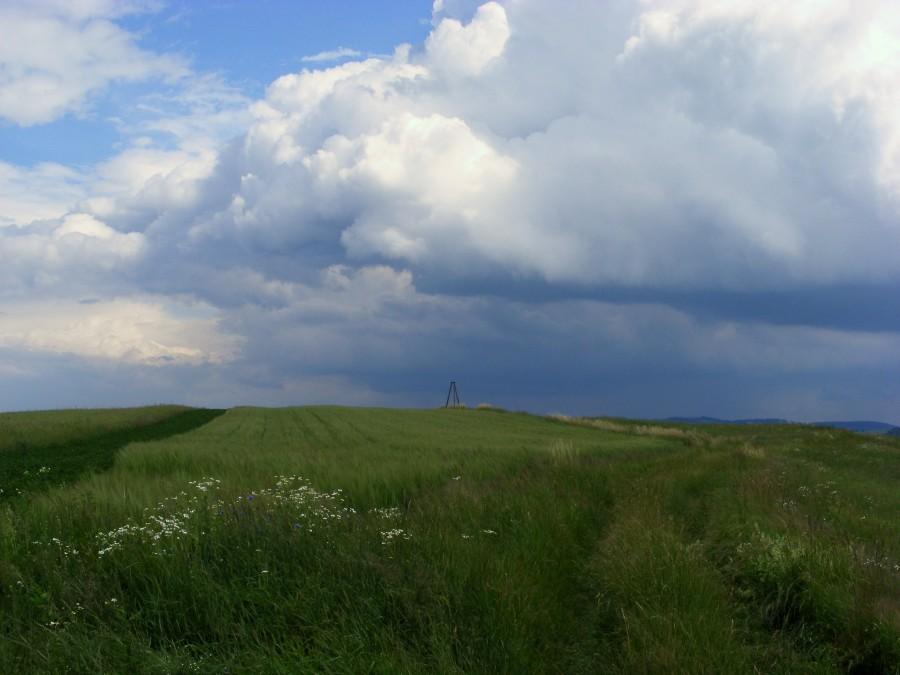 Wieża triangulacyjna wśród pól z szalonym chmurami u góry
