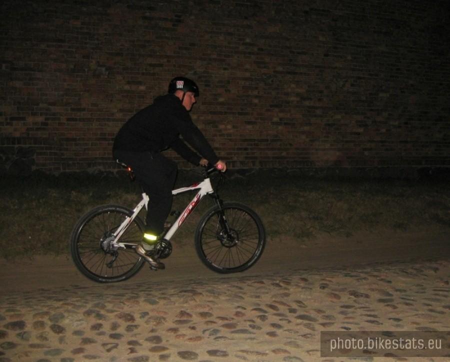 Grigori pod osłoną nocy mknie brukową drogą na swoim nbiałym rowerze.
