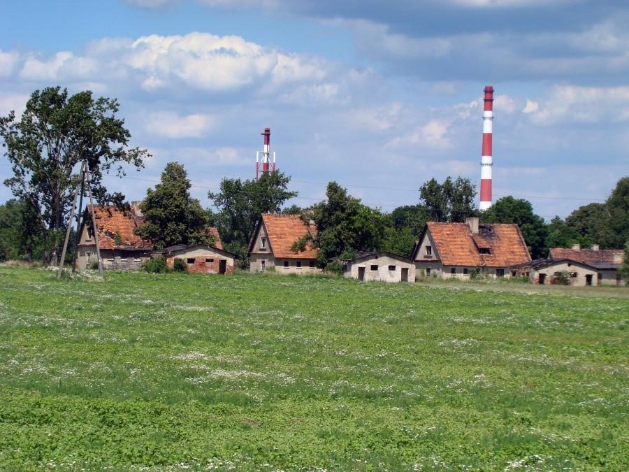 Opuszczone domy we wsi Żukowice. W tle kominy huty miedzi