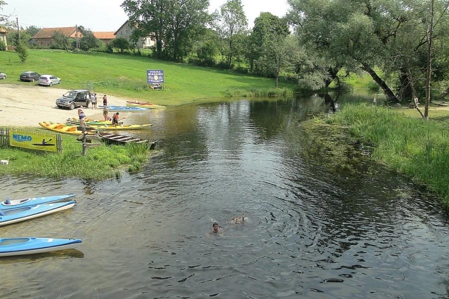 Kajaki na brzegu a ludzie w wodzie