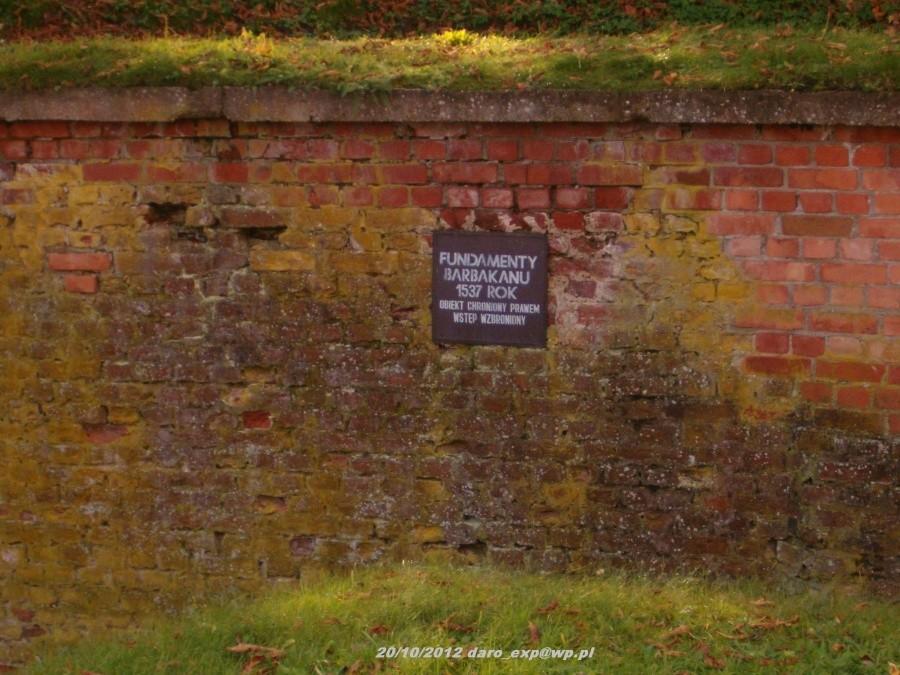 Wycieczka rowerowa. Tczew-Elbląg-Frombork. Tablica informacyjna na temat ruin barbakanu, widok z mostu przed bramą wejściową do kompleksu katedralnego we Fromborku.