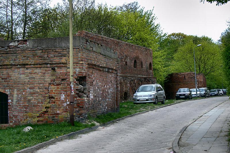 Niezbyt historycznie mury z parkującymi samochodami wyglądają
