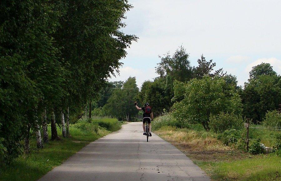 Odjeżdżający rowerzysta z uniesioną ręką