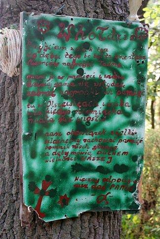 Tablica na drzewie informująca o niegdyś tu istniejącym cmentarzu niemieckim