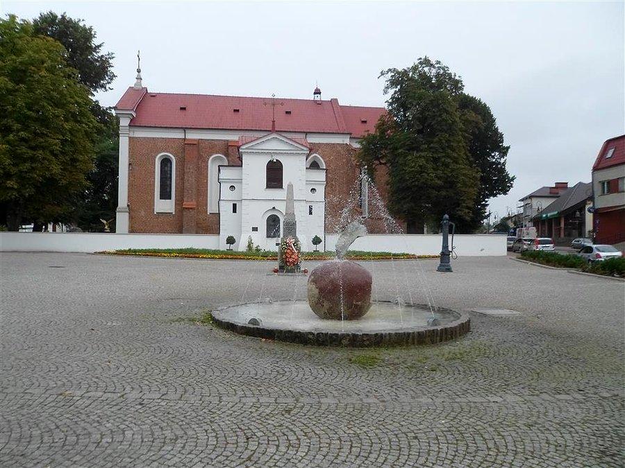 Plac z fontanną, pomnikiem i kosciołem. Tarczyn
