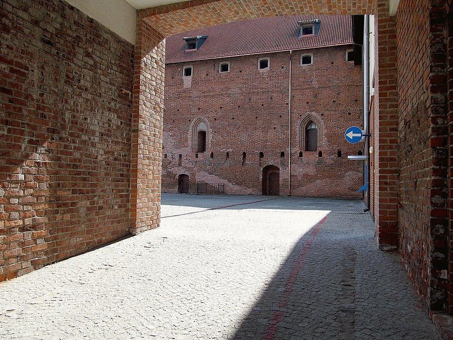 Dziedziniec zamkowy widziany za krat bramy wjazdowej - Działdowo