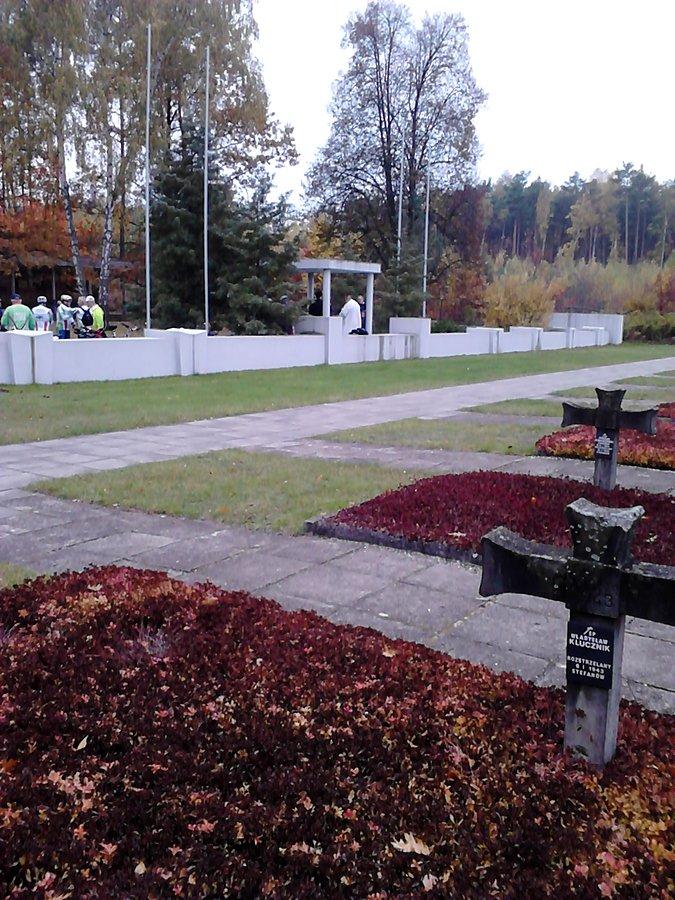 Ksiądz odprawia mszę przed murem cmentarnym