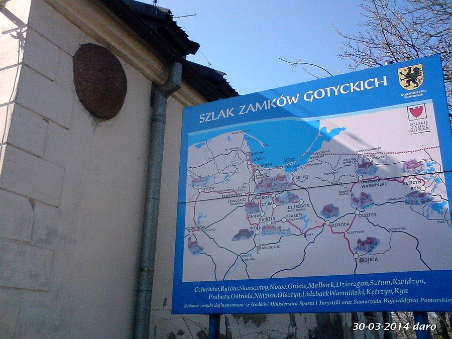 30-03-2014. Przed tablicą informacyjną Szlaku Zamków Gotyckich, przy Zamku Joannitów w Skarszewach. Ciekawostką jest wielka kula kamienna w górnej części ściany Zamku Joannitów, po lewej stronie zdjęcia