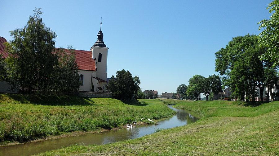 Rzeka dzieląca wioskę na pół - Kierpień. W tle kościół pw. Narodzenia NMP