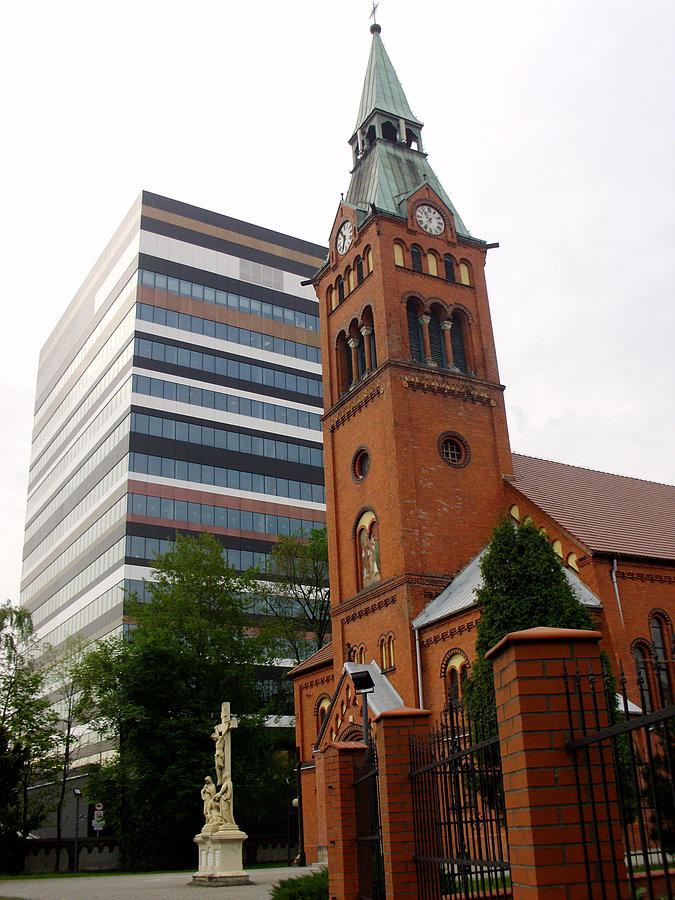 Kościół pod wezwaniem świętych Apostołów Jana i Pawła w Dębiu z nowym biurowcem w tle