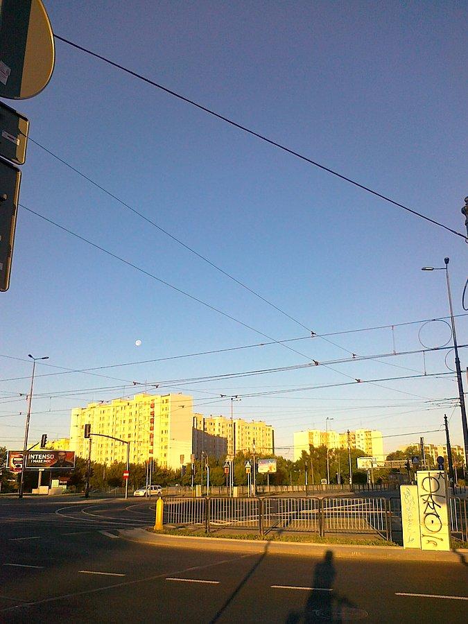 Biały punkcik na niebie nad blokiem to księżyc