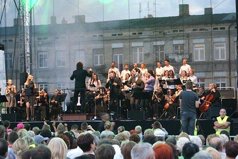 Piotr Rubik z orkiestrą i chórem na scenie na Placu Kościuszki