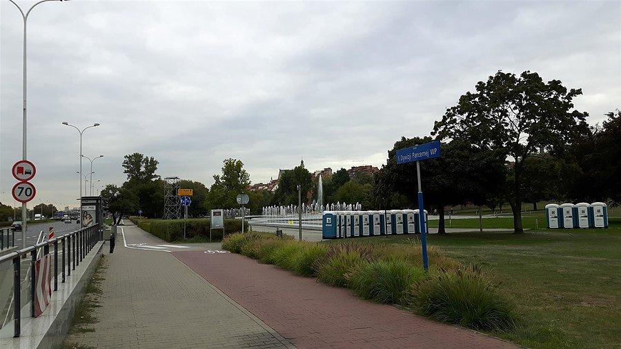 Przenośne toalety z fontanną w tle