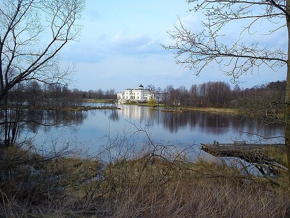Jasna sylwetka pałacu w Bielawie odbija swój wizerunek w lustrze wody stawu