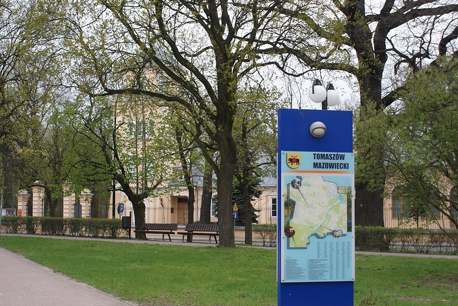 Tablica informacyjna na tle pałacu Ostrowskich - siedziby muzeum tomaszowskiego