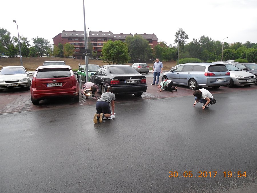 Taka akcja pod Lidlem w Chorzowie: klika osób usiłuje wyciągnąć kota, który wlazł pod samochód