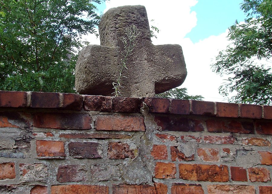Wykonany z piaskowca krzyż pokutny w przykościelnym murze w Kotli. Widok od strony kościoła