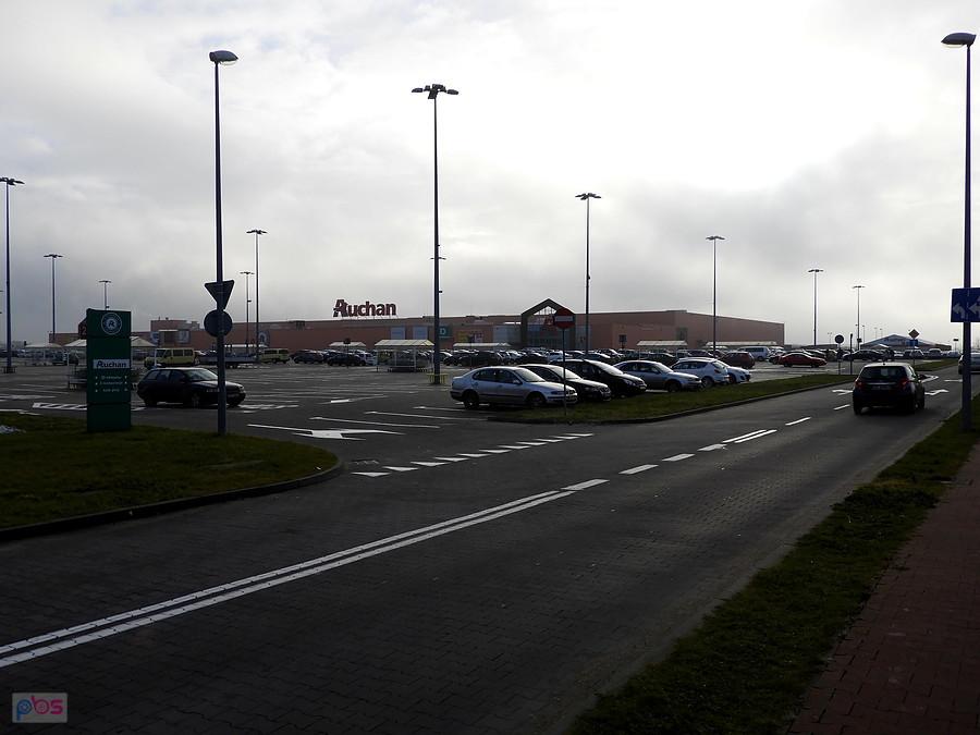 W oddali obiekt marketu Auchan - mnóstwo aut na parkingu.