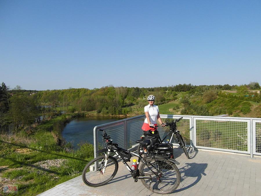 Rowerzystka z dwoma rowerami na moście nad rzeką