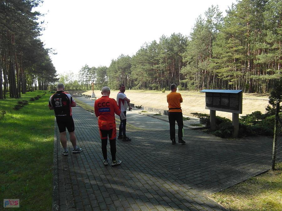 Grupa rowerzystów przy tablicy pamięci w lesie