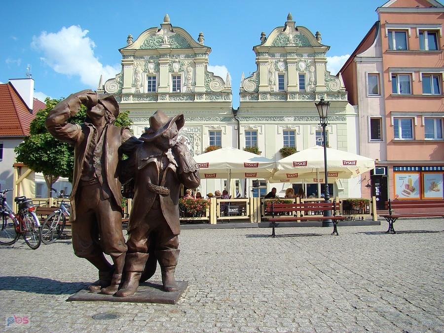 Figura czarnego kota i chwiejącego się na nogach jegomościa.