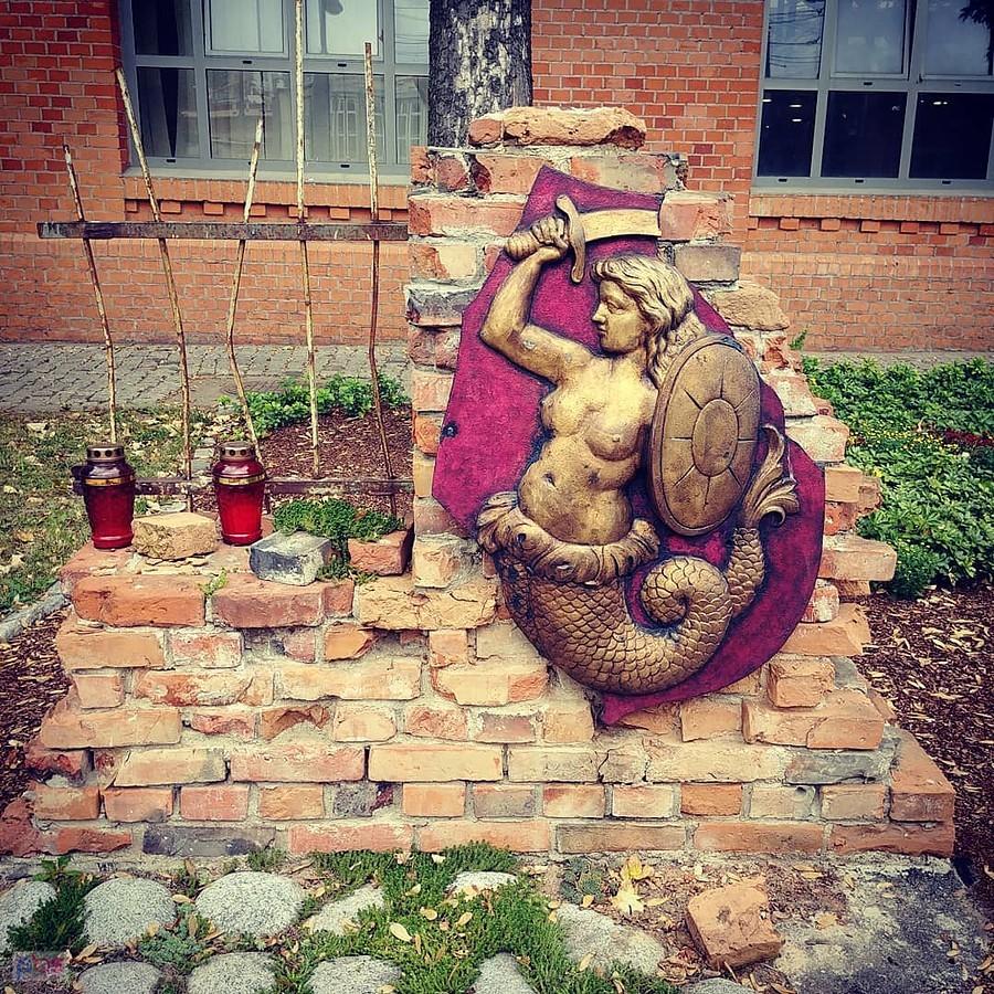 Syrena z tarczą na ceglanej ścianie