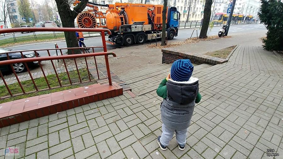 Dziecko obserwuje maszynę wodociągową na ulicy