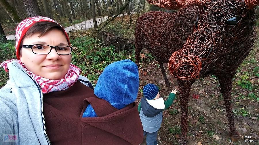 Kobieta z niemowlakiem przy rzeźbie konia w lesie