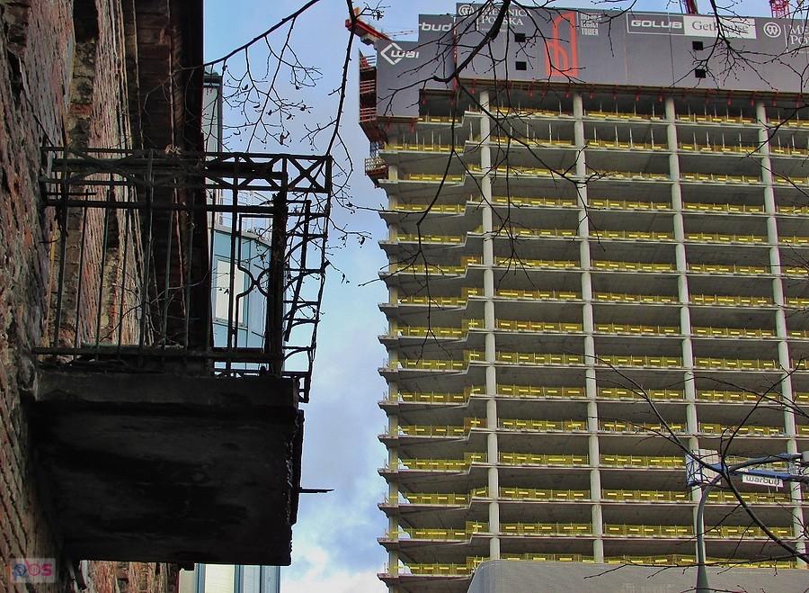 Balkon zrujnowanej przedwojennej kamienicy i budowa nowoczesnego biurowca