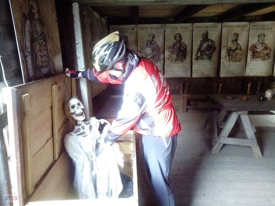 Rowerzysta ogląda szkielet w zabytkowej izbie