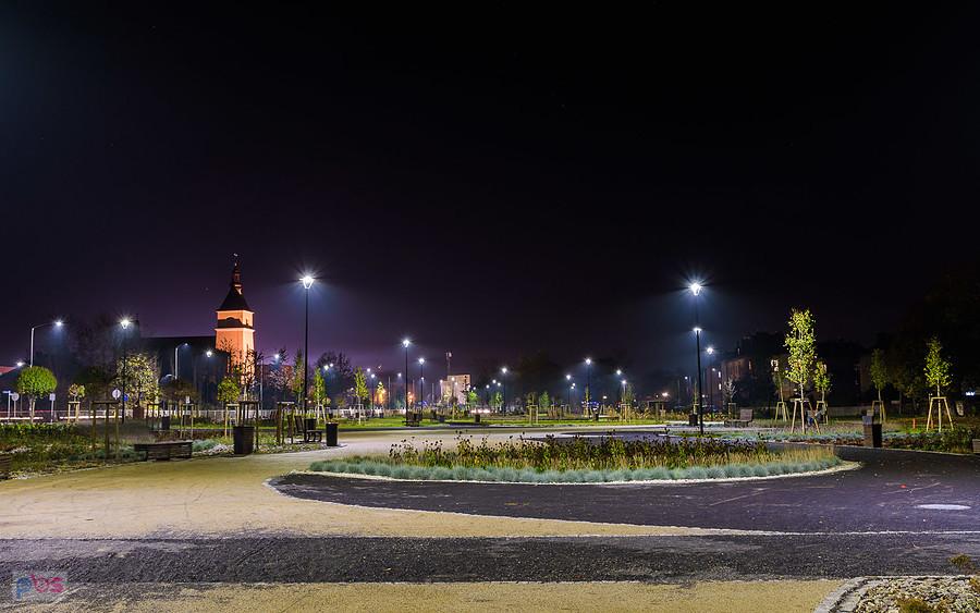 Park miejski w Blachowni wieczorową porą. W tle parafia Świętego Michała Archanioła.