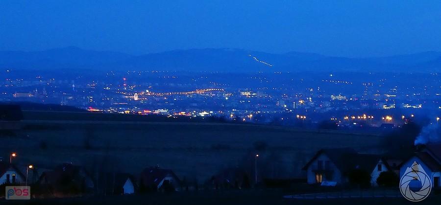 panorama marnego Krakowa znad wiosek jurajskich, od lewej: Wawel, jakiś komin, diabelski młyn nad Wisłą,jakiś wyciąg w oddali, masa nowych osiedli i smog z komina na pierwszym planie