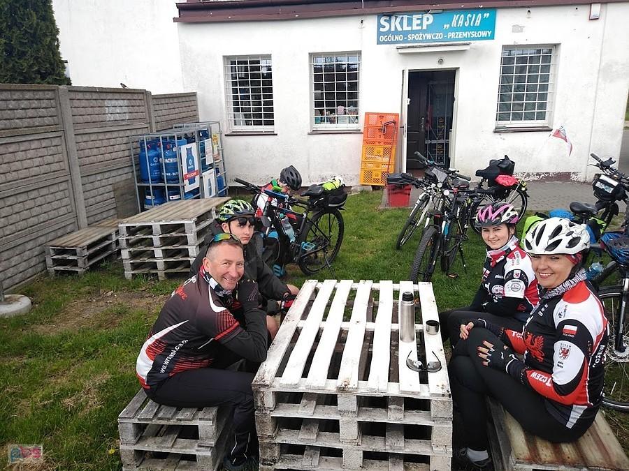 Grupa rowerzystów podczas postoju przy sklepie