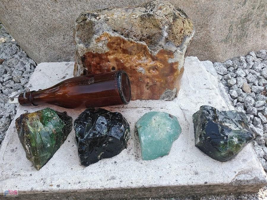 Butelka i odłamki szkła na kamiennej podstawce