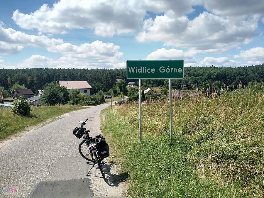 Rower trekkingowy na wiejskiej drodze przy znaku miejscowości