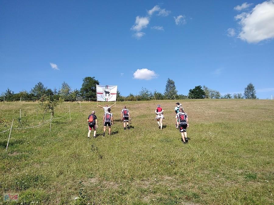 Grupa biegaczy z flagą na wzgórzu