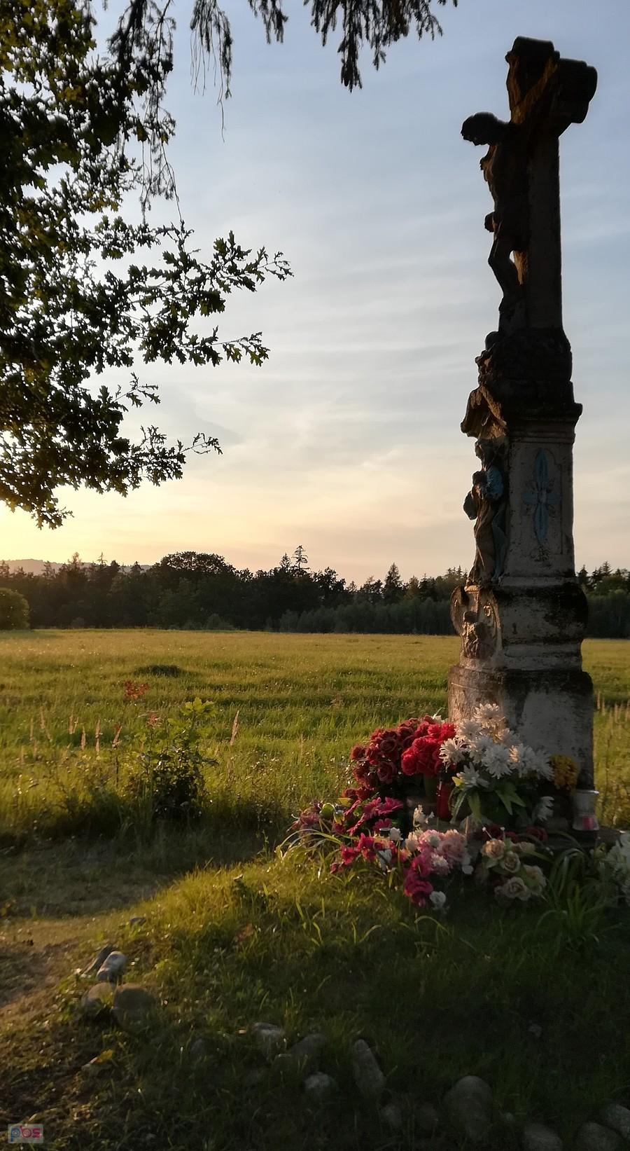 Zabytkowy, kamienny krzyż w blasku wieczornego słońca