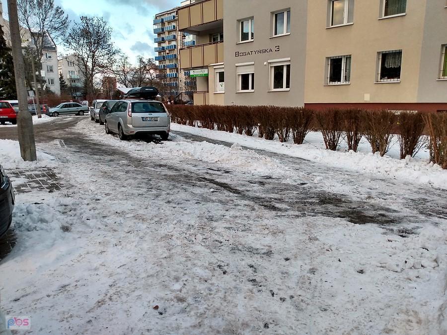 Zimowa ulica osiedla z zaparkowanymi samochodami