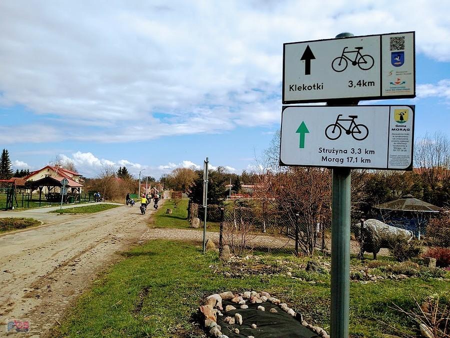 Rowerzyści na wiejskiej drodze ze znakami rowerowymi