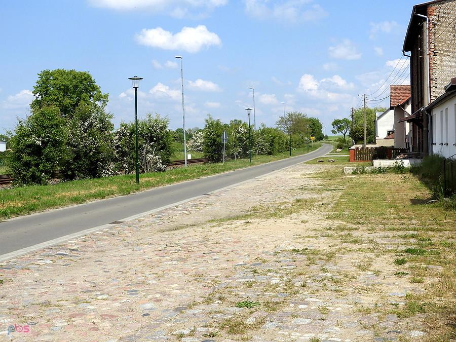 Wiejska droga brukowana przy zabudowaniach