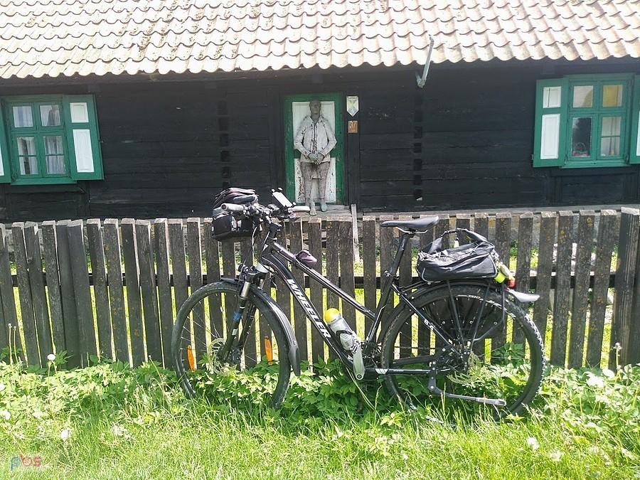 Rower trekkingowy z sakwami przed drewnianym domem na Mazurach