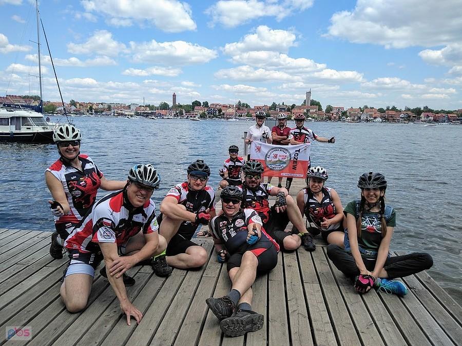Grupa rowerzystów nad jeziorem w Mikołajkach