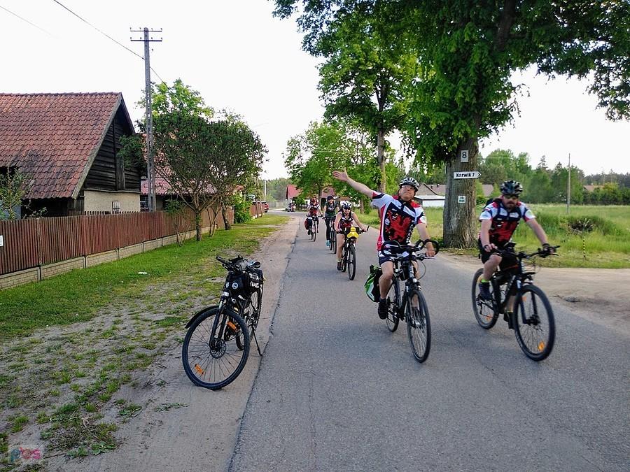 Grupa rowerzystów na wiejskiej drodze
