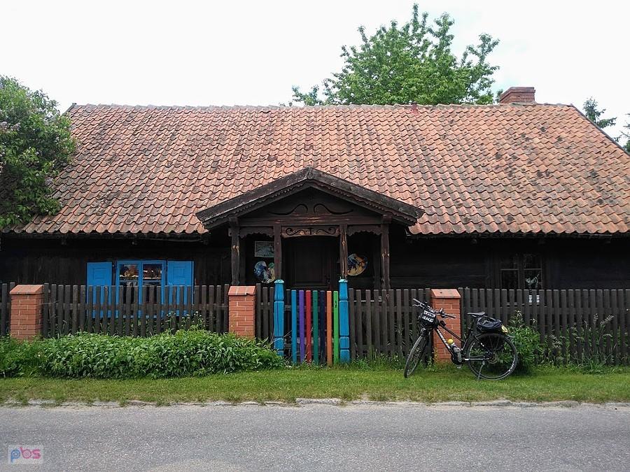 Drewniany dom z kolorową bramą w Wojnowie