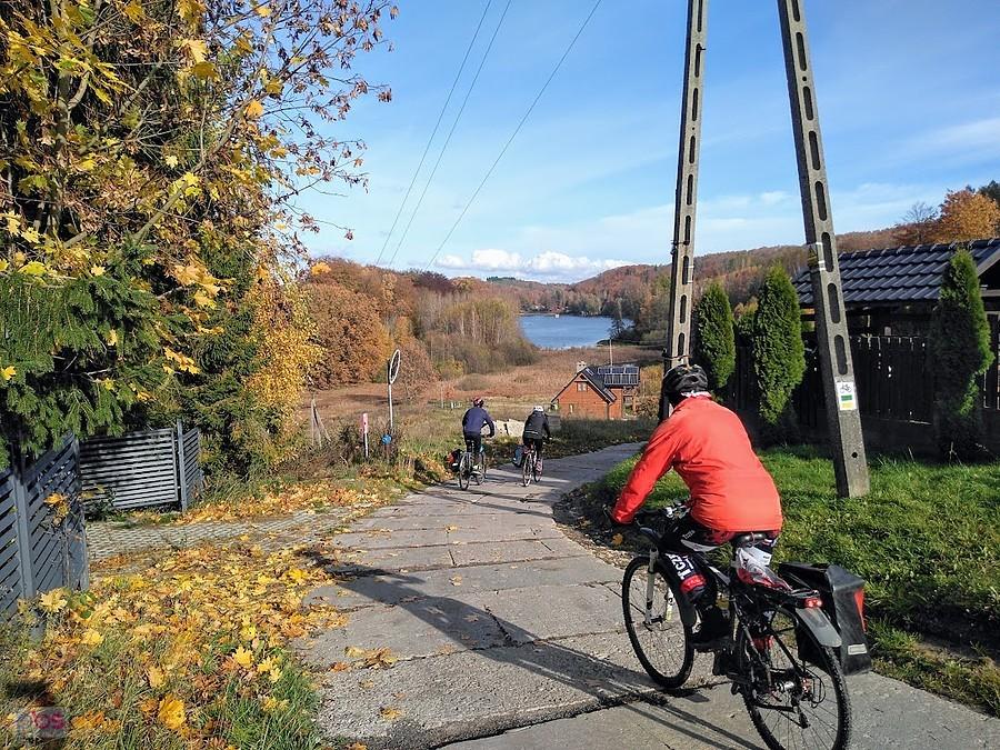 Rowerzyści na jesiennym szlaku przy jeziorze