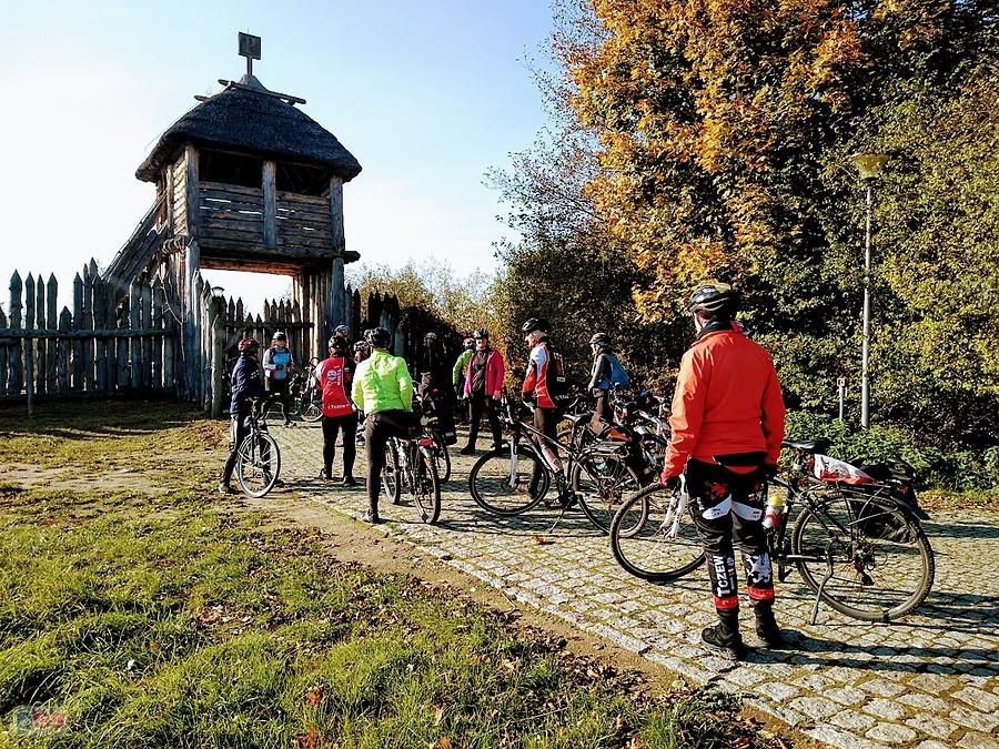 Grupa rowerowa przed drewnianą bramą