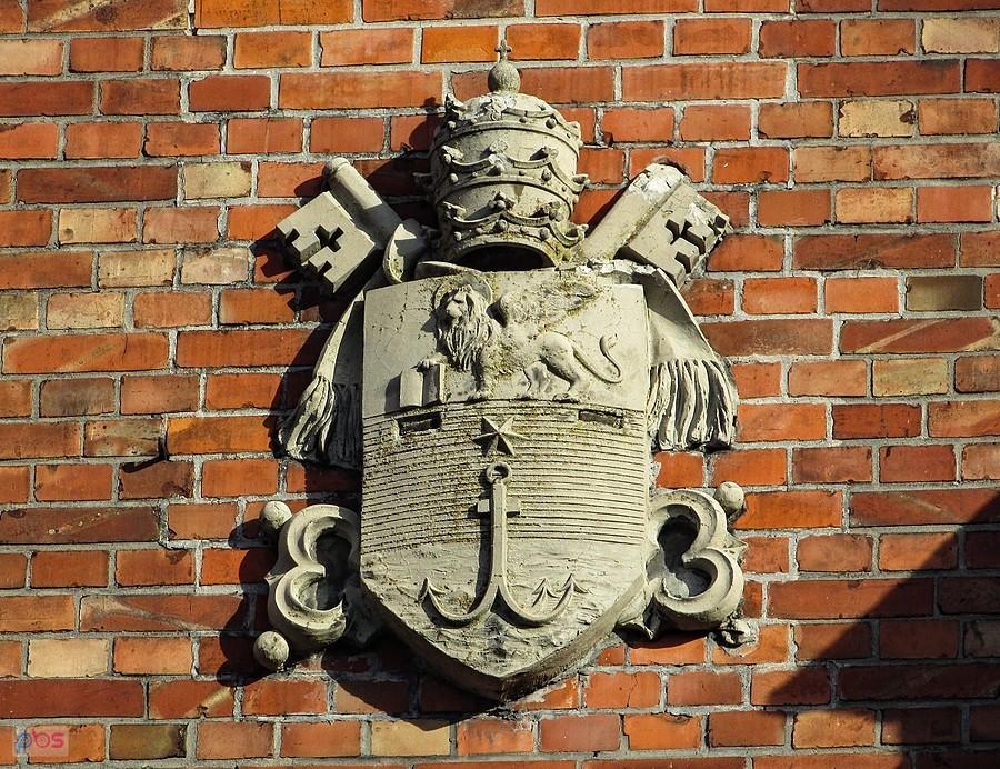 Herb papieża Piusa X na fasadzie kościoła w Osiecku