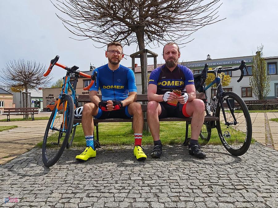 Dwóch kolarzy odpoczywa na ławce z rowerami