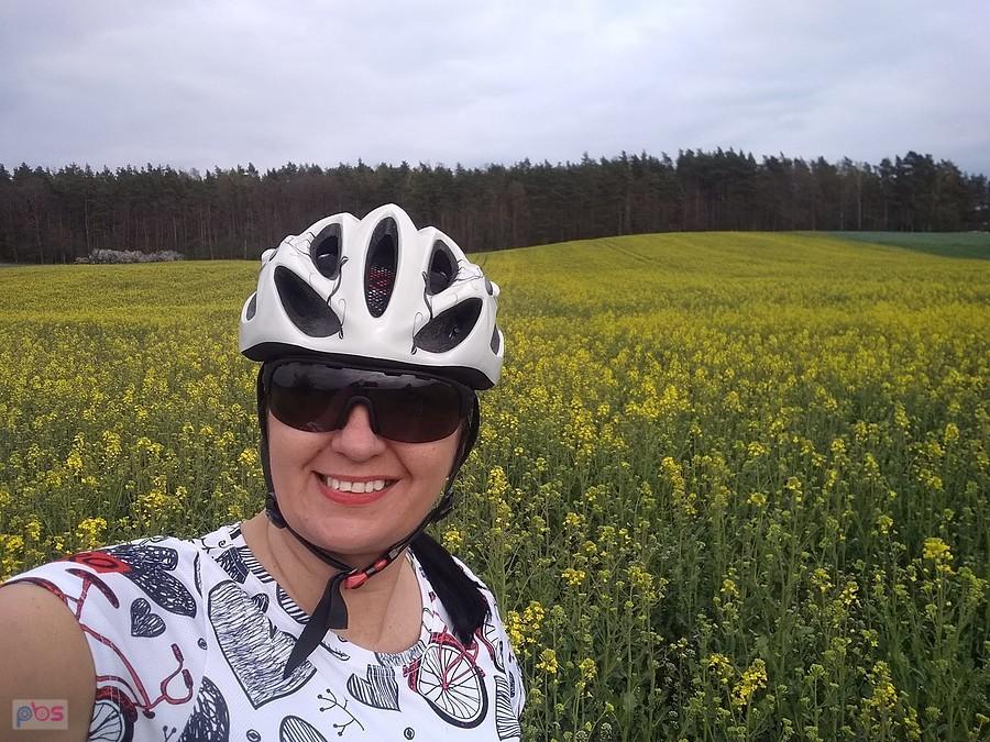 Rowerzystka na polu kwitnącego rzepaku